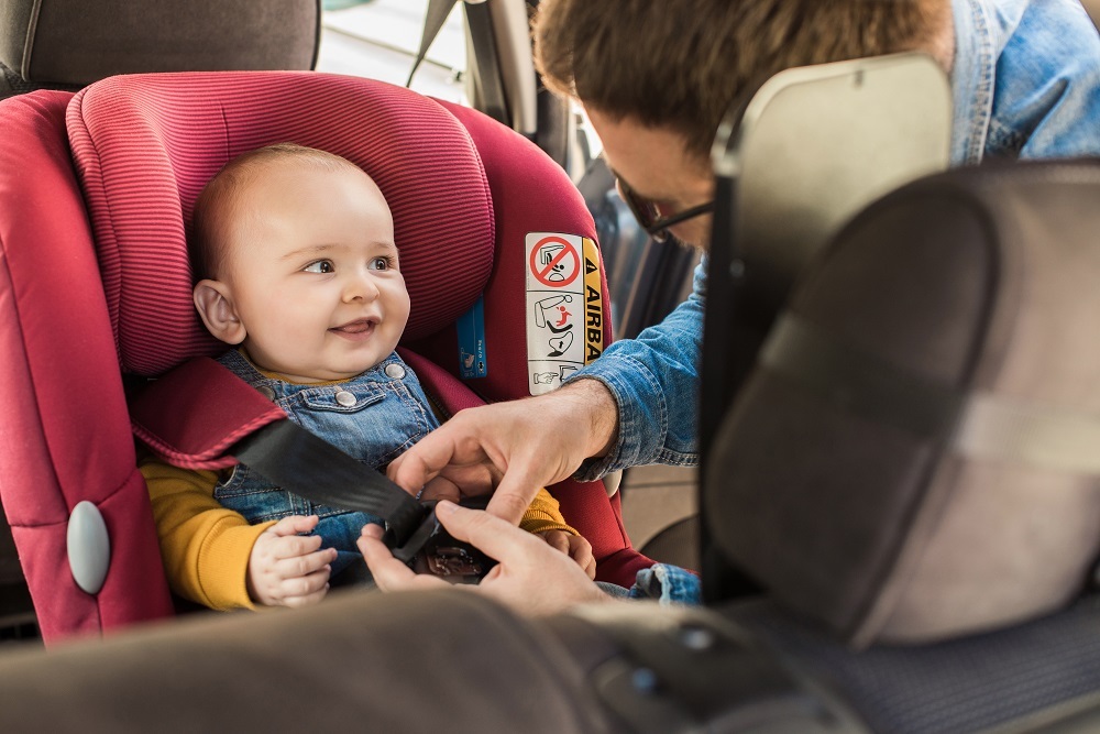 Happy baby sitting on her car seat for safety.