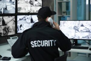 Male security guard talking by telephone in surveillance room.