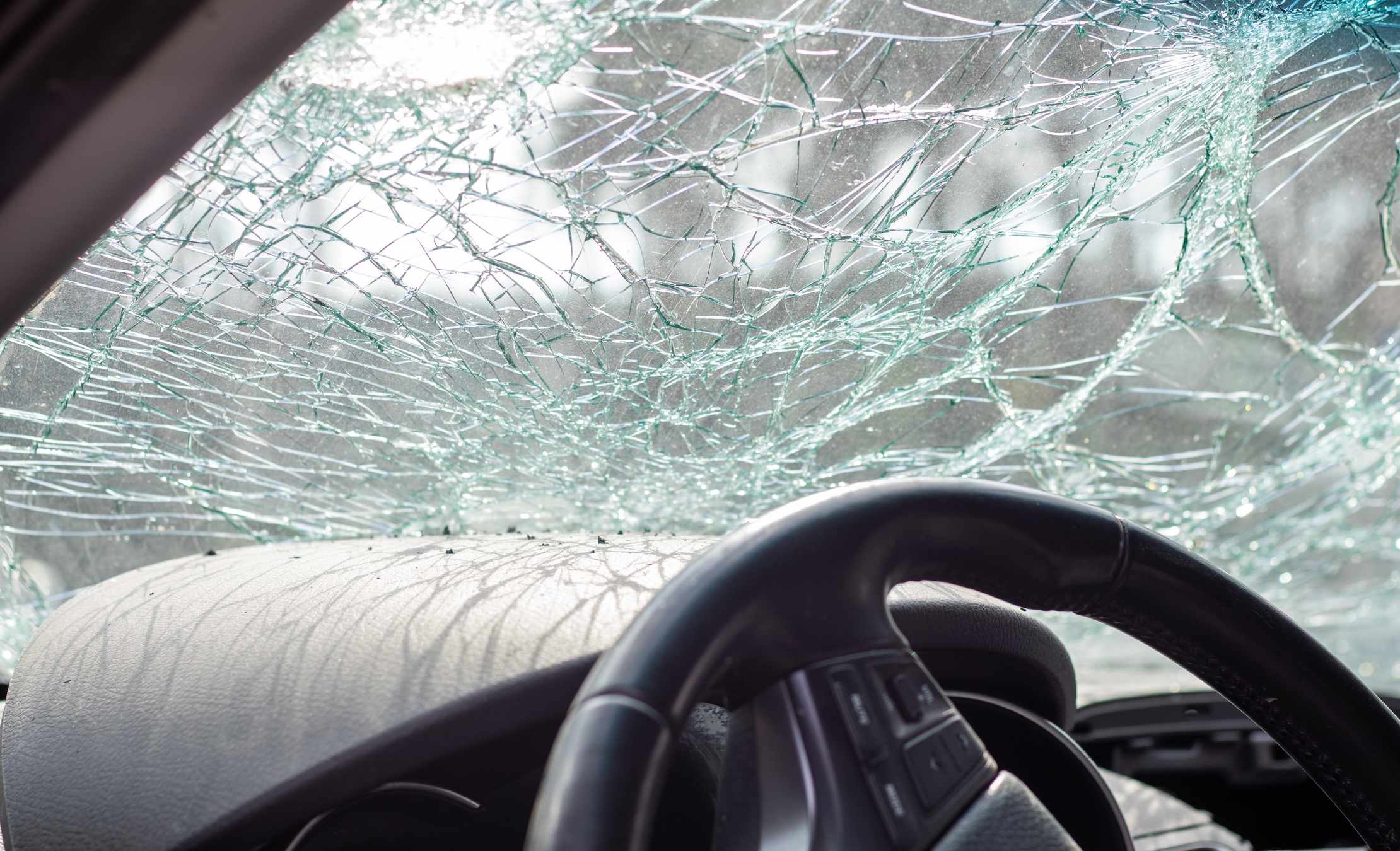 Damaged car window after an accident. Broken windshield as a result of an accident, inside view. Cabin interior details, view from the cab. Safe movement. Broken windshield. Glass crack and damage.