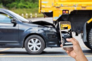 Woman taking photo of car accident in the road.