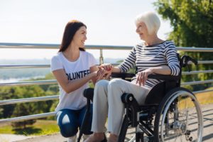Female volunteer chatting with woman in wheelchair.