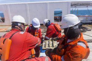 Offshore workers helping each other in pulling the anchor.