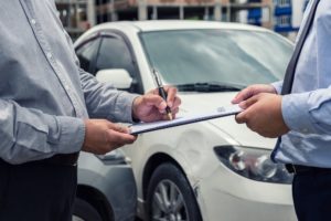 Insurance agent checking on the car damages from accident.