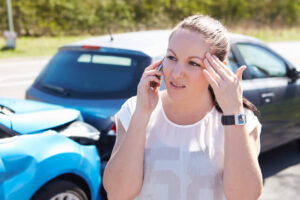 Female driver involved in car accident calling police to report car accident.