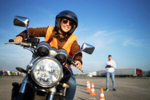 Female student with helmet taking motorcycle lessons and practicing ride.